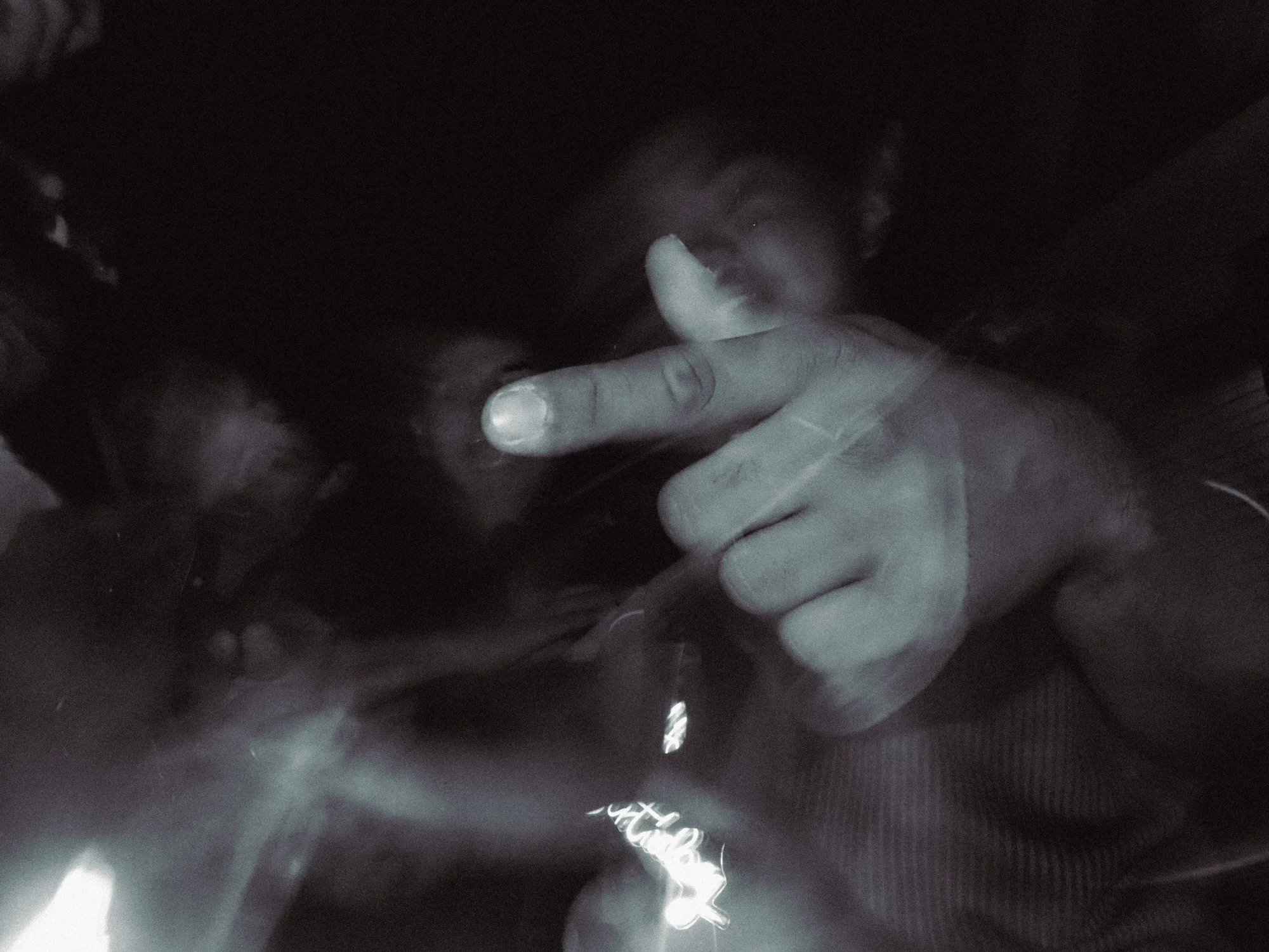 Hand gesturing in the dark, light catching fingers and smoke