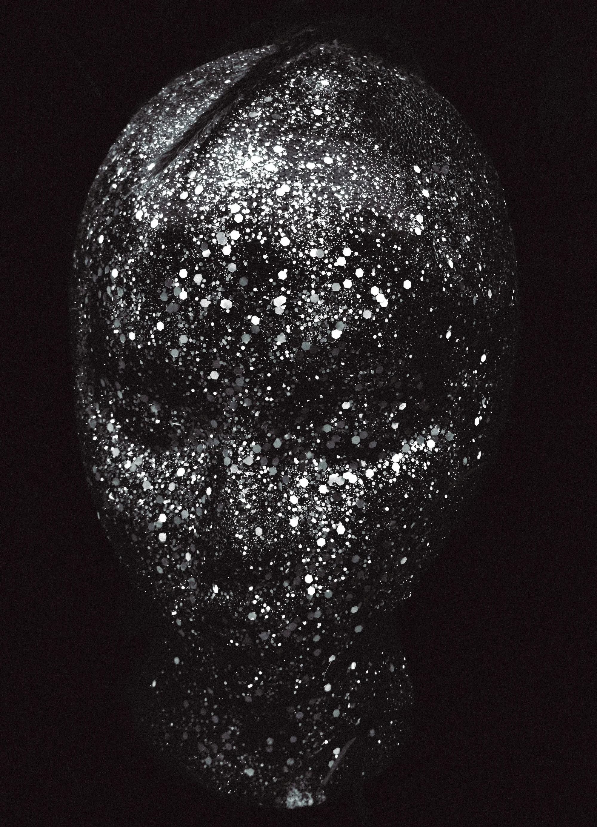 Glitter-covered face emerging from blackness